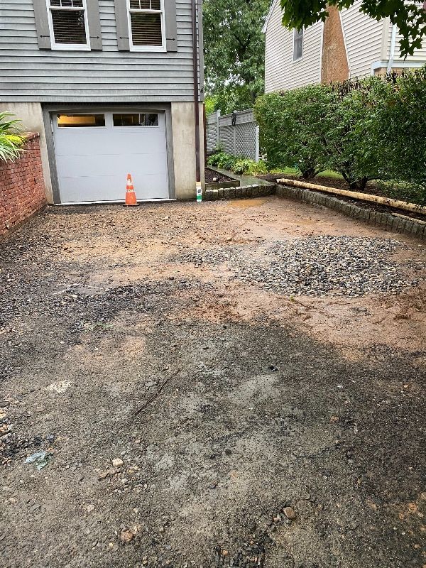 A driveway with a white garage door and a gravel driveway in front of a house.