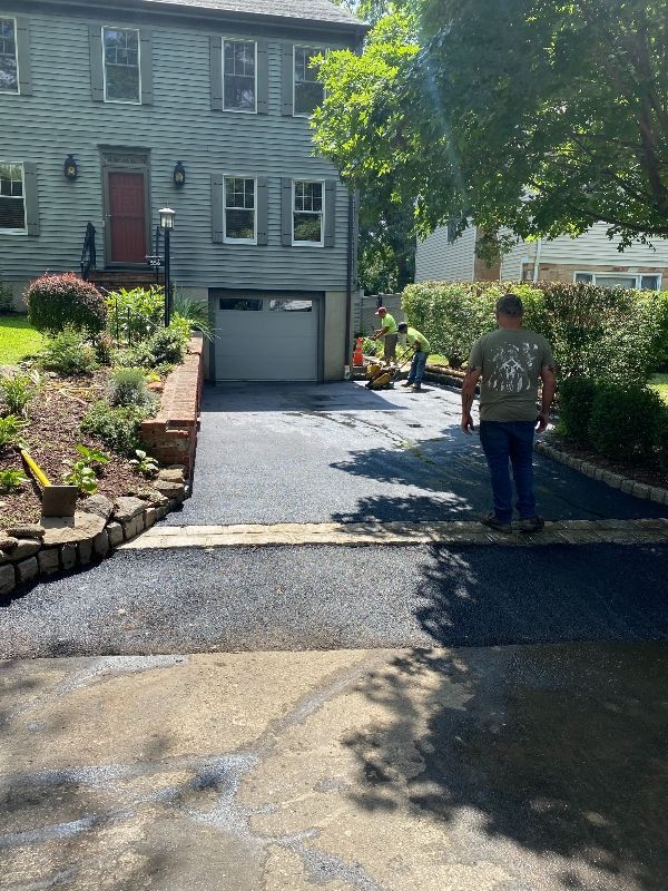 A man is walking down a driveway in front of a house.