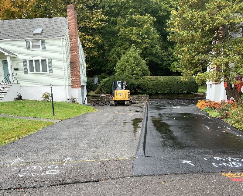 A yellow bulldozer is parked in front of a house