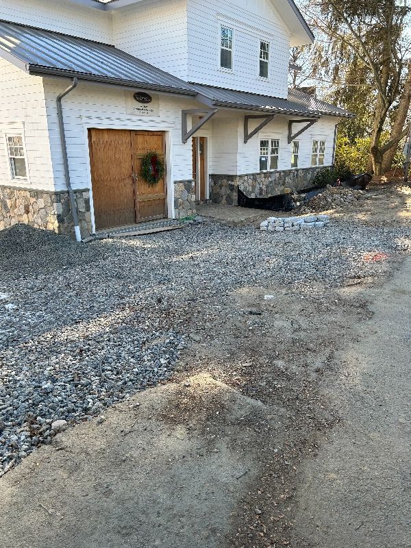 A large white house with a gravel driveway in front of it.