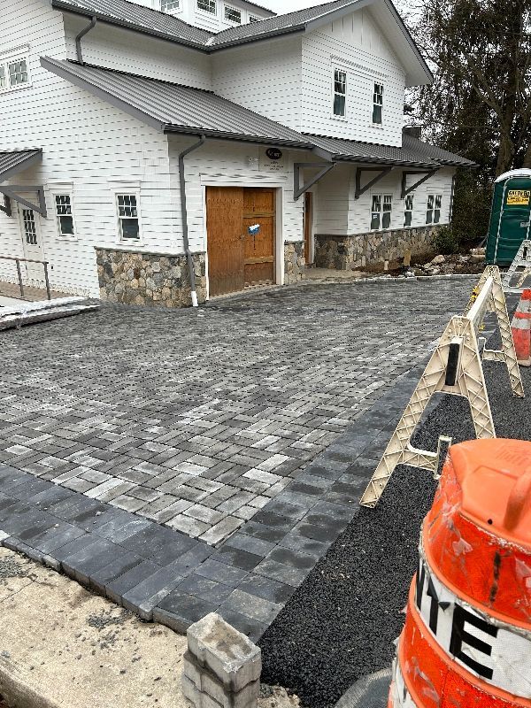A large white house with a brick driveway in front of it.