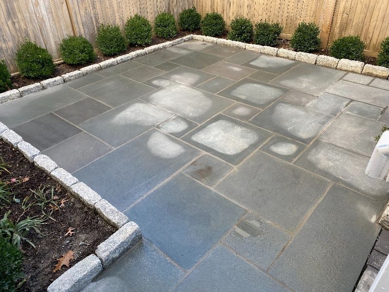 A stone patio with a wooden fence in the background.