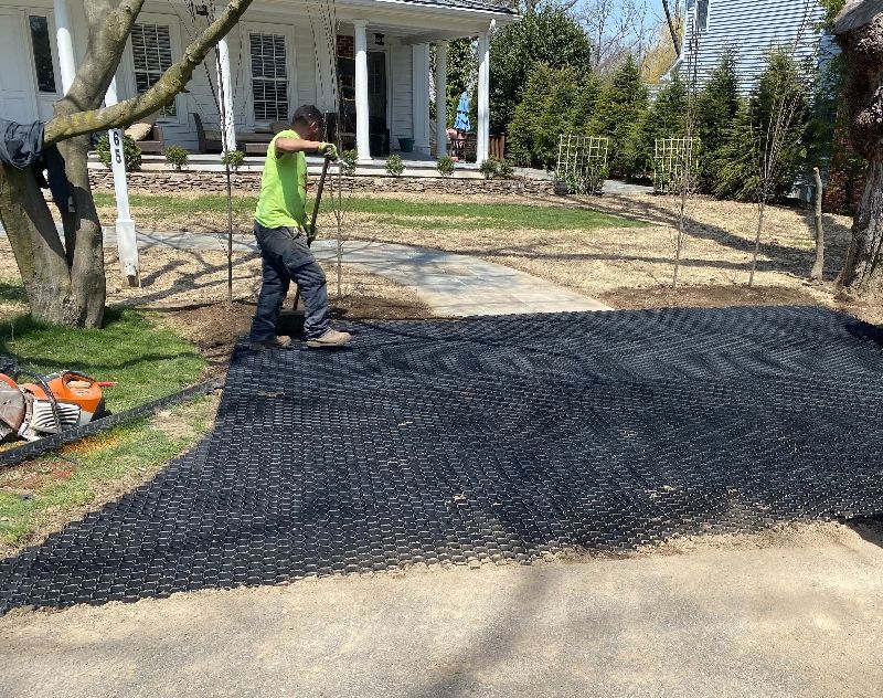 A man is working on a driveway in front of a house.