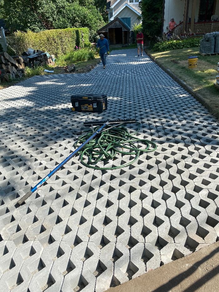 A man is walking down a brick driveway next to a toolbox.