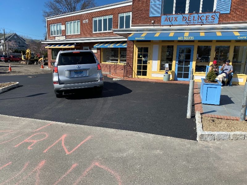 A car is parked in front of a store called aux delices
