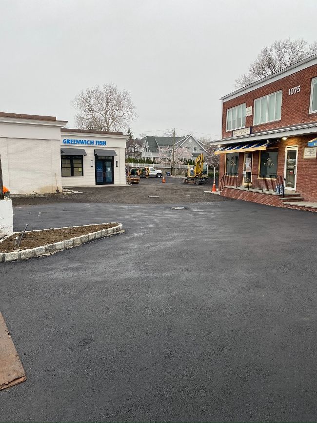 A large empty parking lot with a brick building in the background.