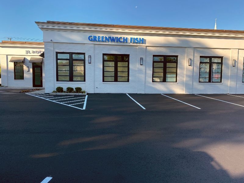 A white building with a blue sign that says greenwich fish