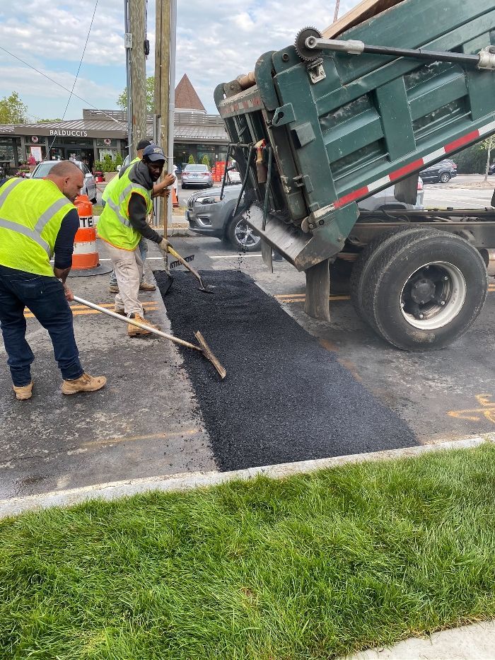 Two men are working on a road next to a dump truck.