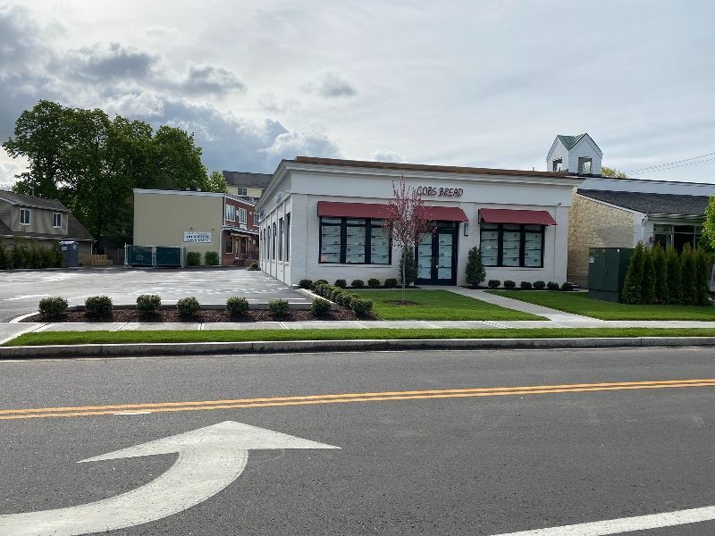 A white building with a red awning is on the side of the road.