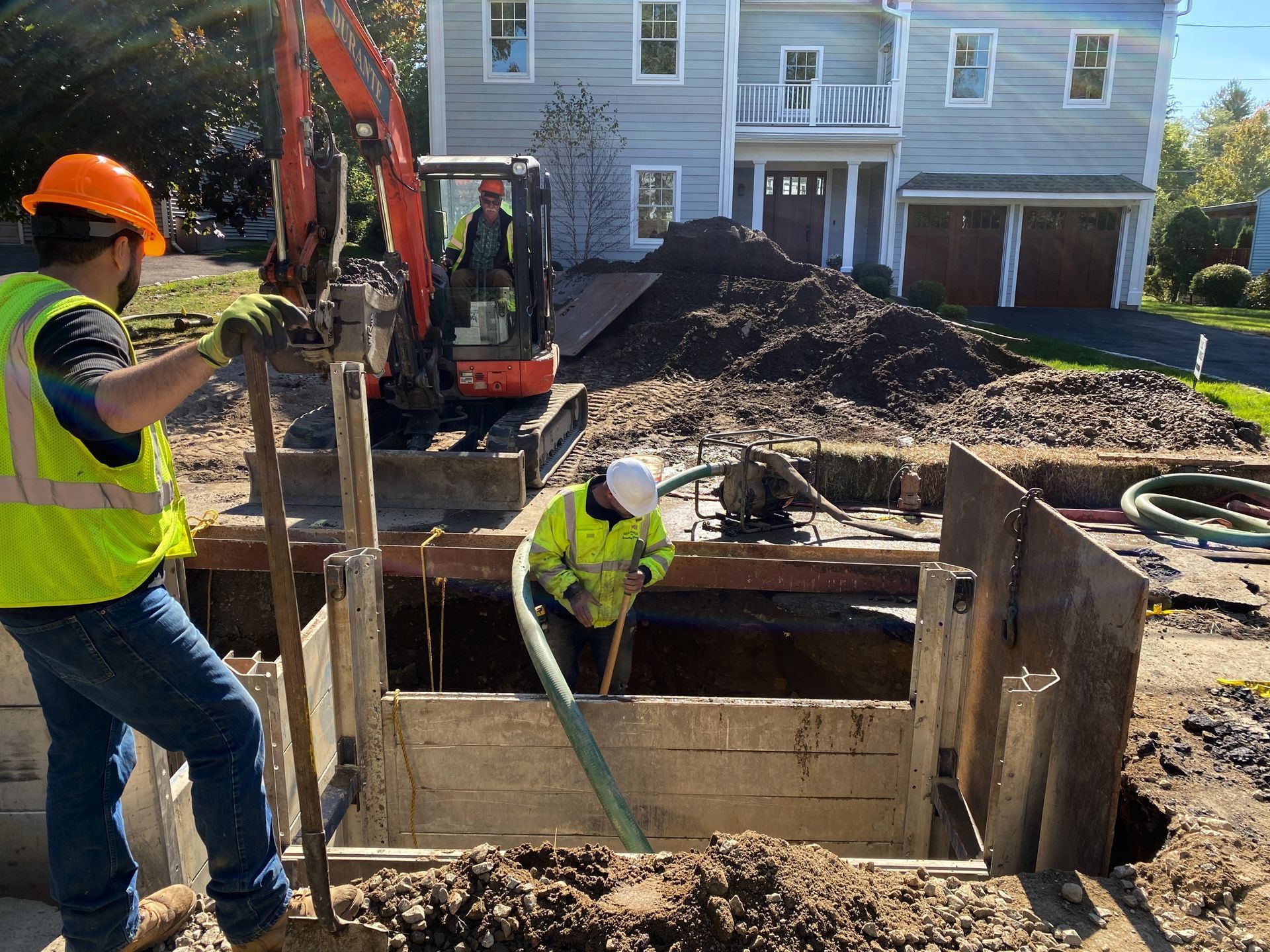 Two construction workers are working on a construction site in front of a house