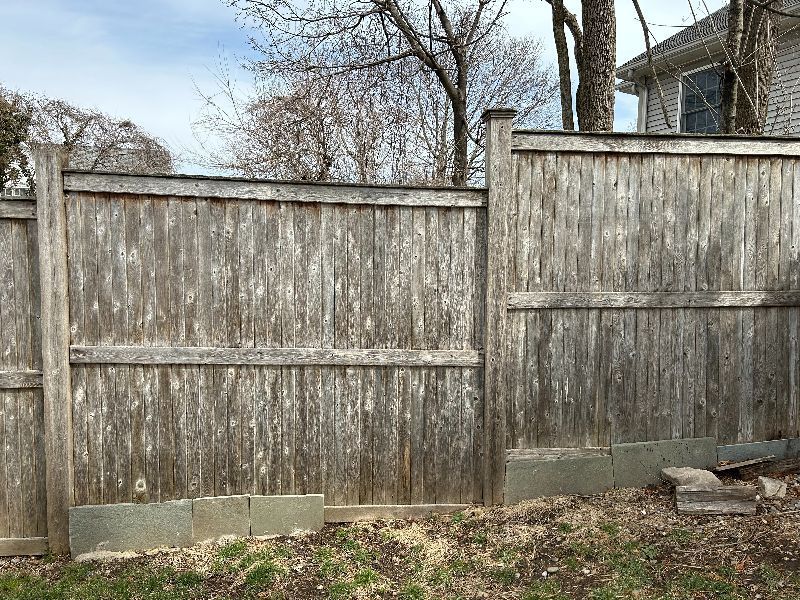 A wooden fence is in the backyard of a house.