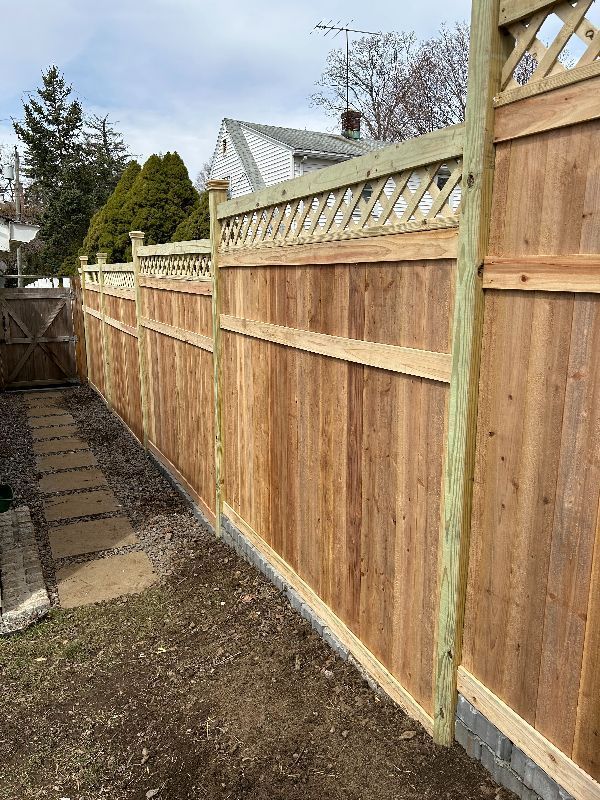 A wooden fence is sitting in the backyard of a house.