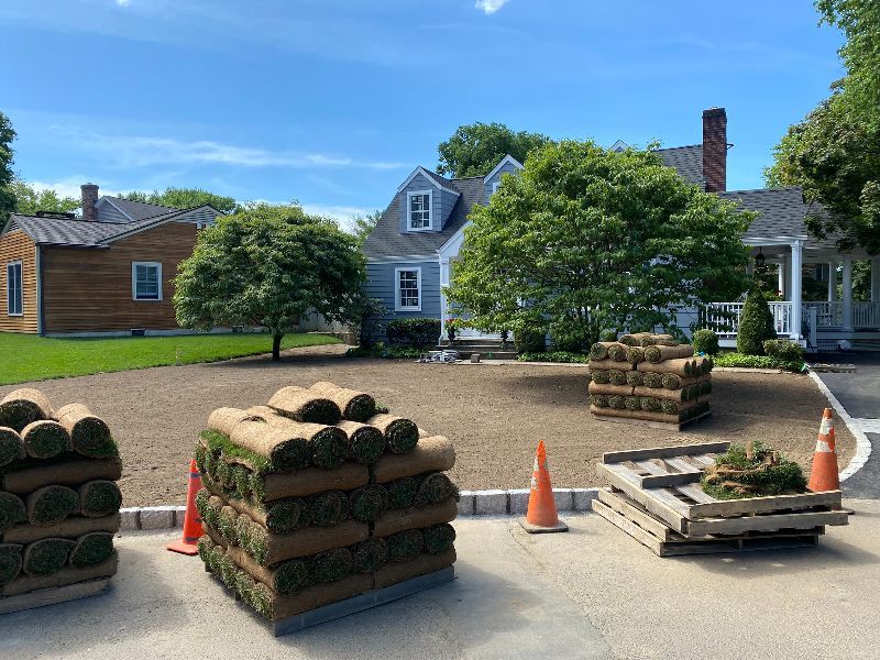 A bunch of rolls of grass are sitting in front of a house.