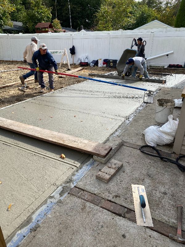 A group of construction workers are working on a concrete driveway.
