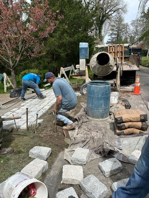 A group of construction workers are working on a sidewalk.