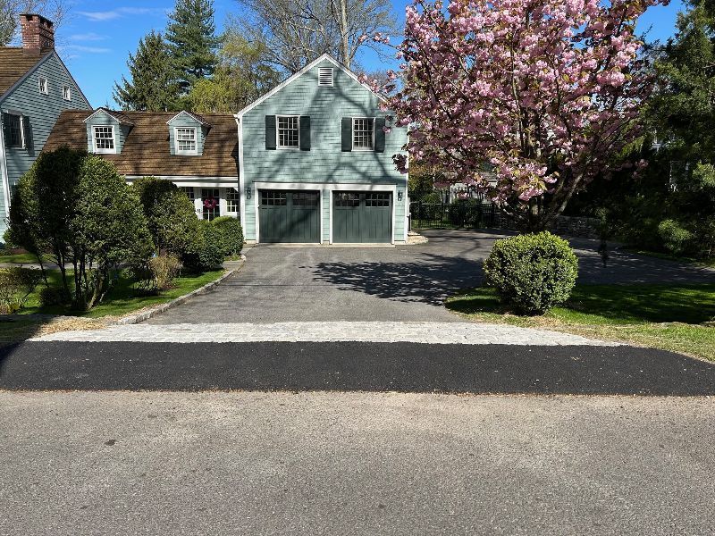A house with two garage doors and a cherry blossom tree in front of it