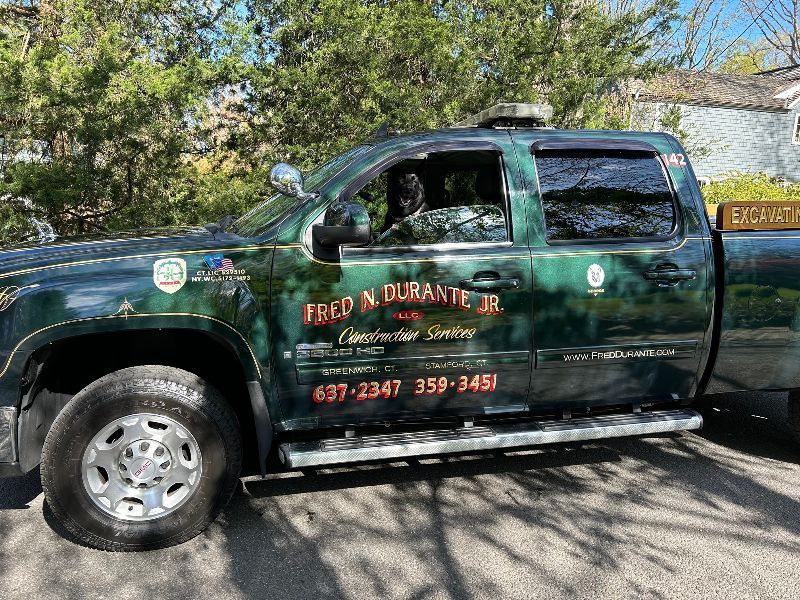 A green truck is parked on the side of the road.