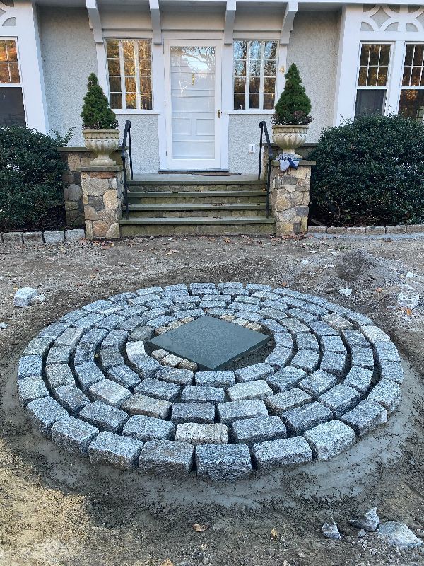 A stone circle is being built in front of a house.