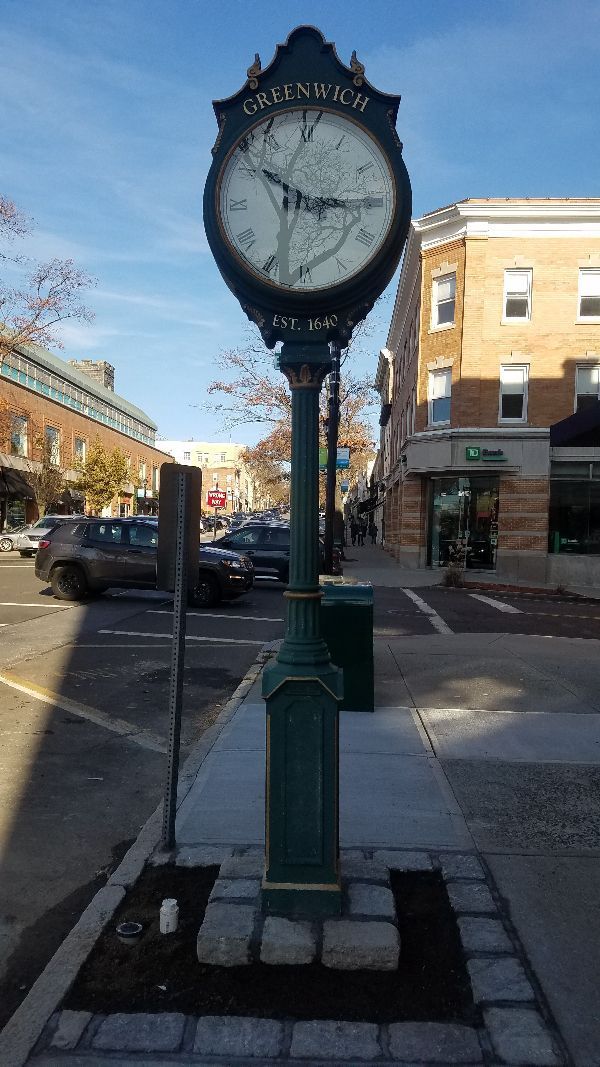 A clock on a pole in the middle of a city street.