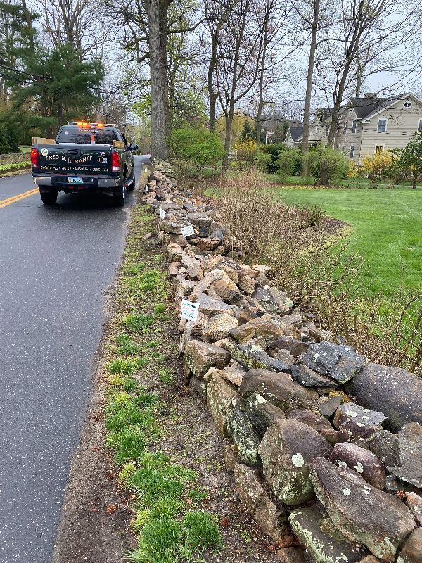 A truck is driving down a road next to a stone wall.