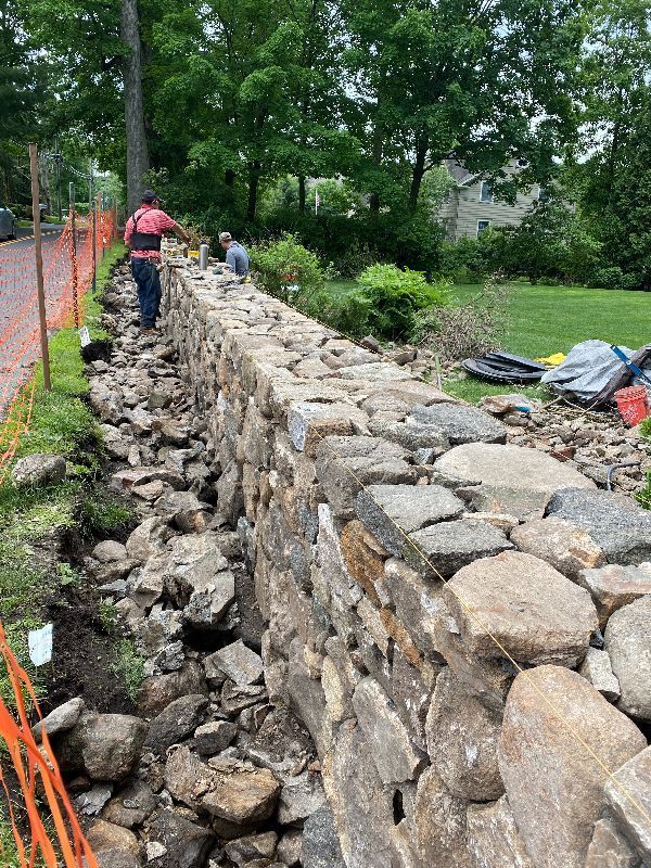 A stone wall is being built in the yard.