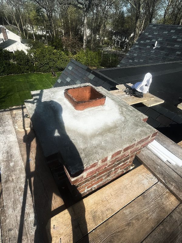 A brick chimney is sitting on top of a wooden deck.