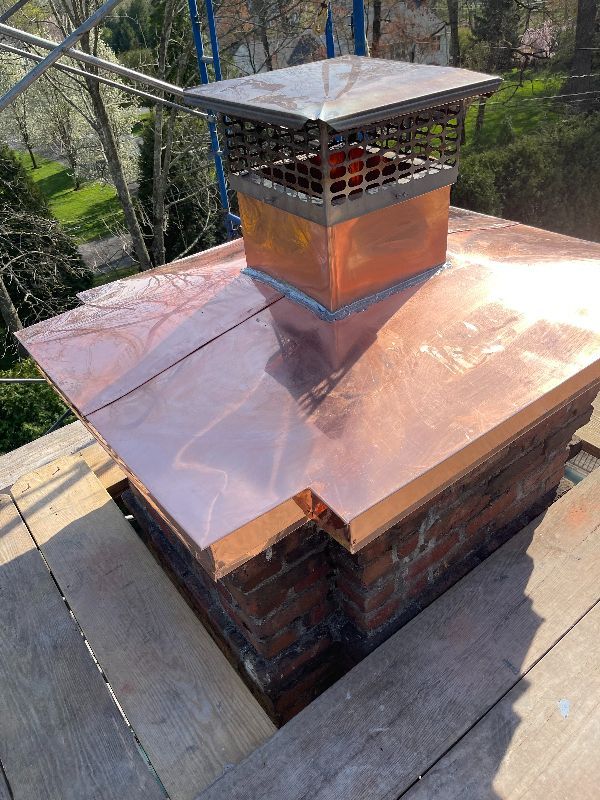 A copper chimney cap is sitting on top of a brick chimney.