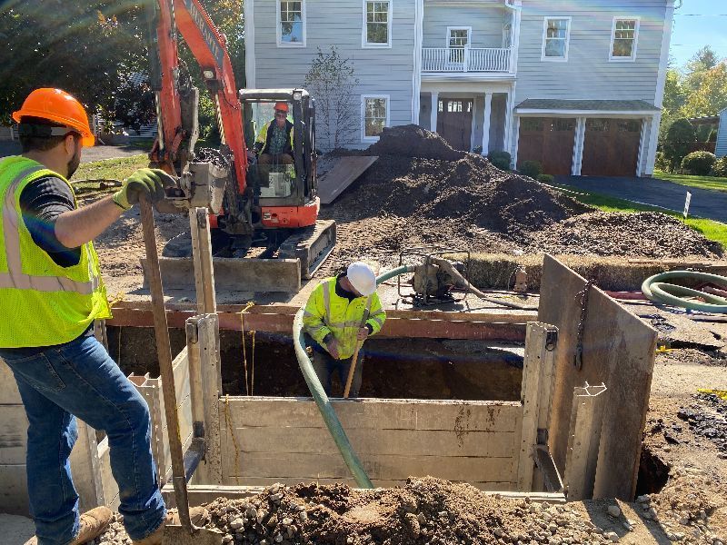 Two construction workers are working on a construction site in front of a house.