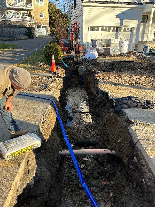 A man is digging a hole in the ground next to a blue pipe.