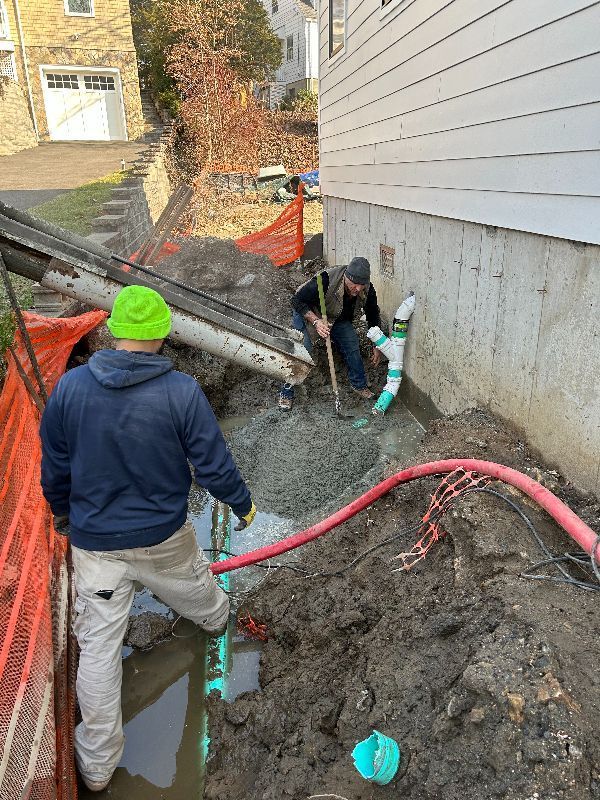 A couple of men are standing in the mud next to a house.