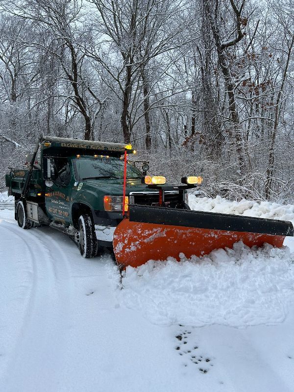A snow plow is plowing snow on a snowy road.