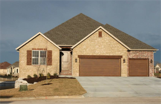 A large brick house with two brown garage doors
