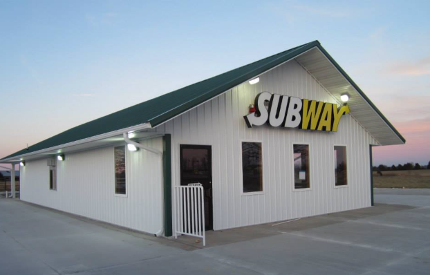 A white building with a green roof that says subway