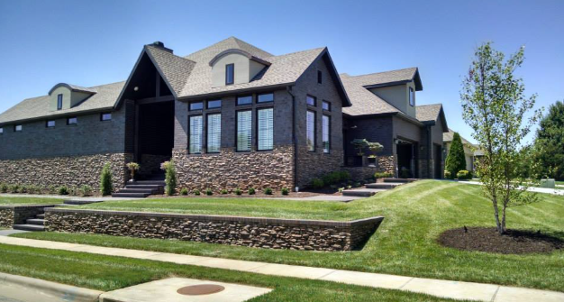 A large house with a lot of windows is sitting on top of a lush green lawn.