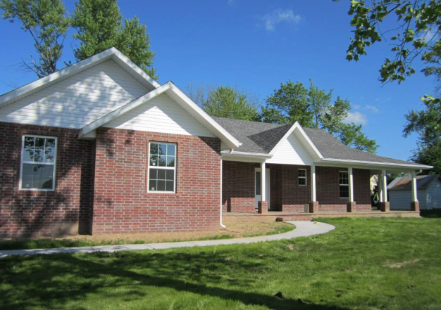 A brick house with a porch and a walkway in front of it