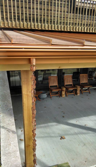 A patio with chairs and tables under a wooden roof.