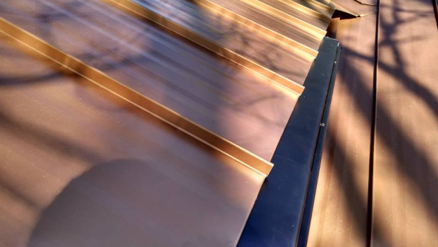 A close up of a copper roof with a tree shadow on it