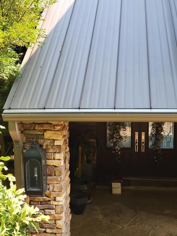 A house with a metal roof and a stone pillar