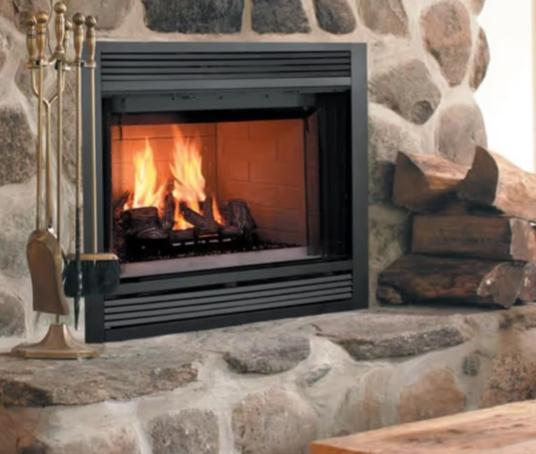 Stone fireplace with a black insert and a small fire burning inside, surrounded by rustic rock veneer.