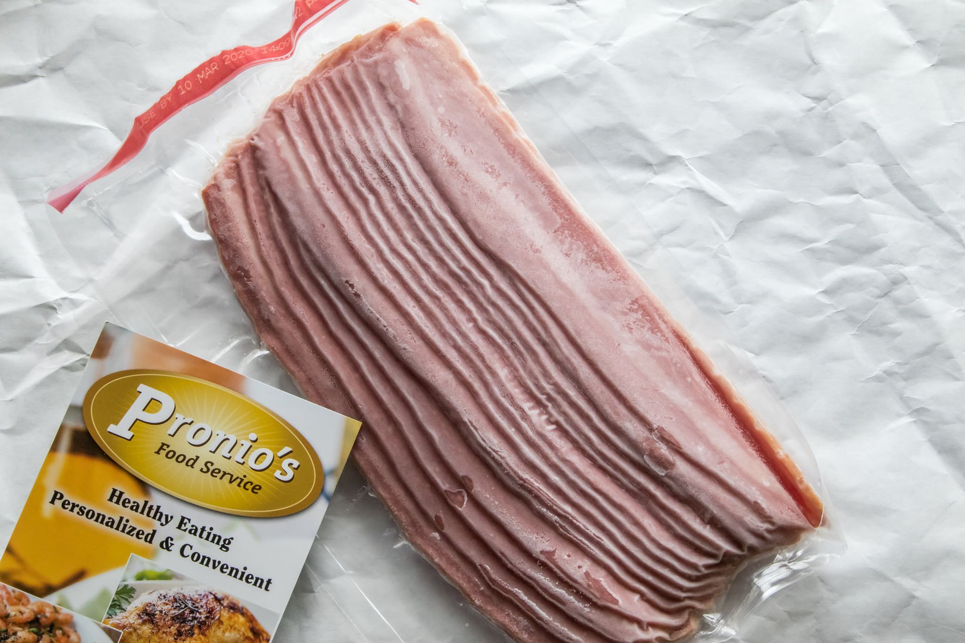 A bag of bacon is sitting on top of a piece of paper.