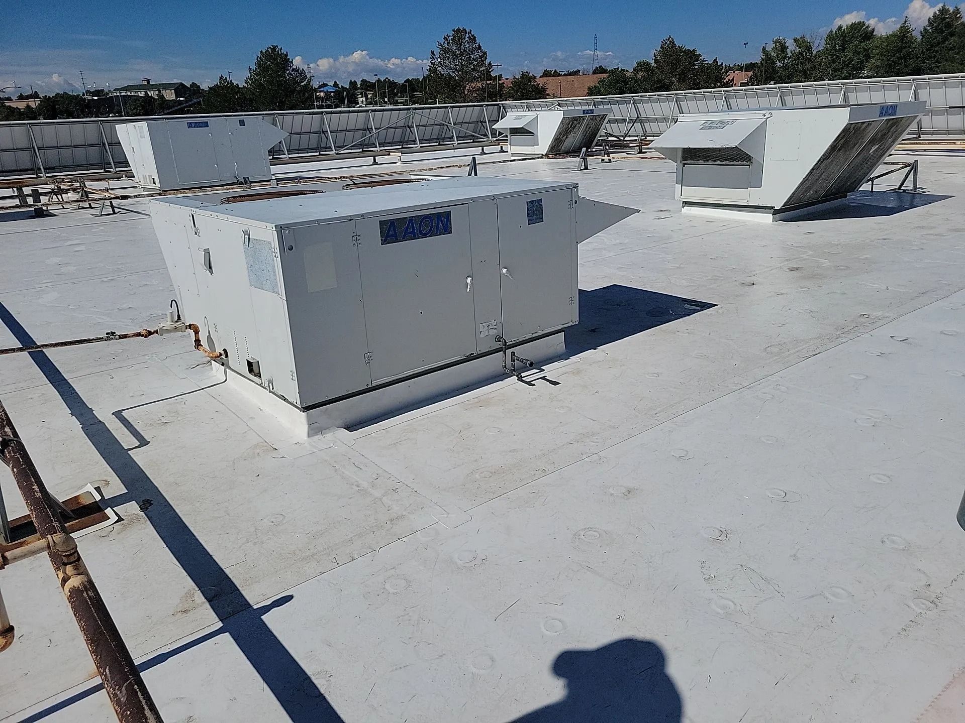White rooftop with HVAC units, a sunny day.