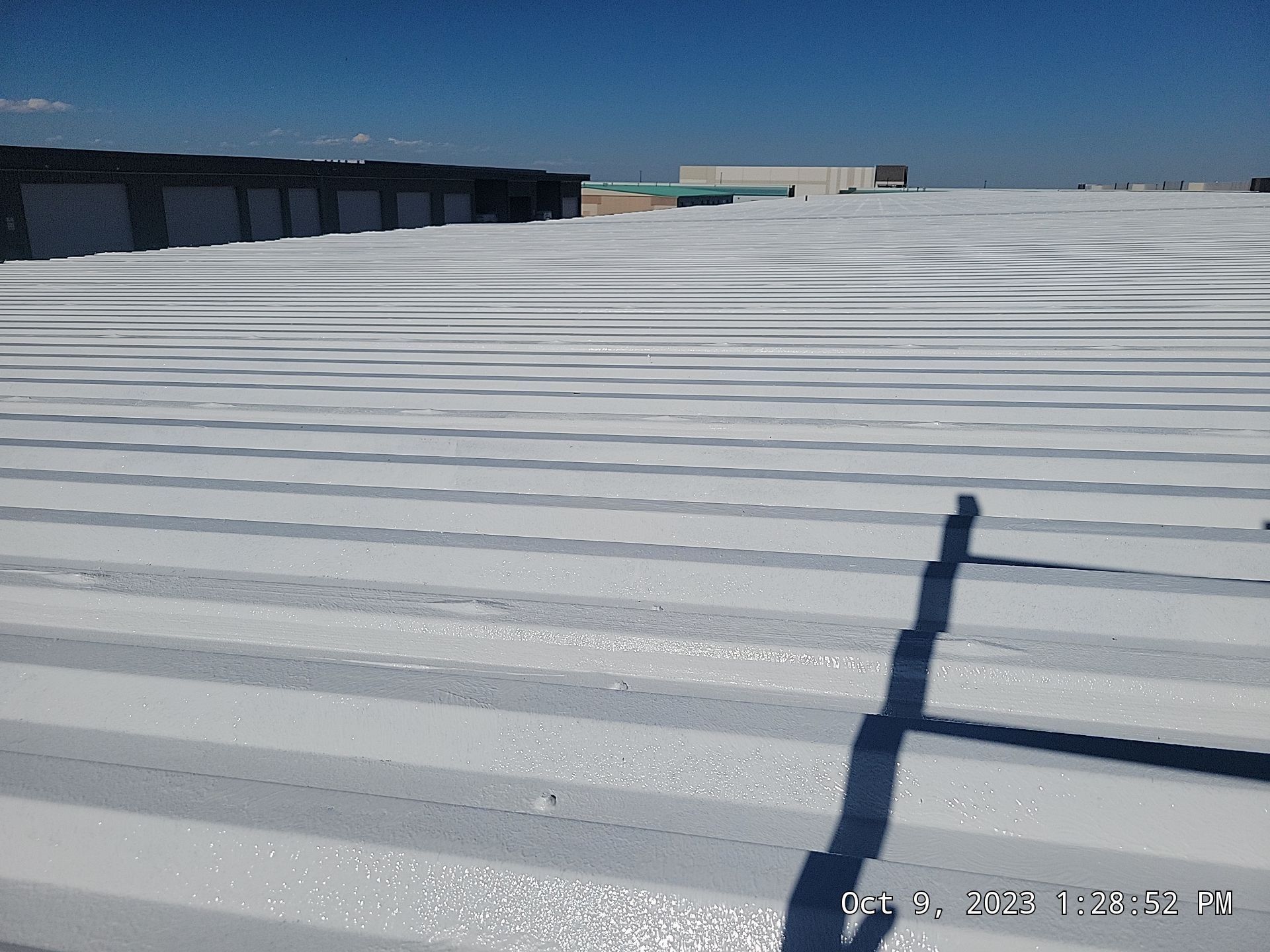 White roof of a building under a blue sky. Shadow in foreground.