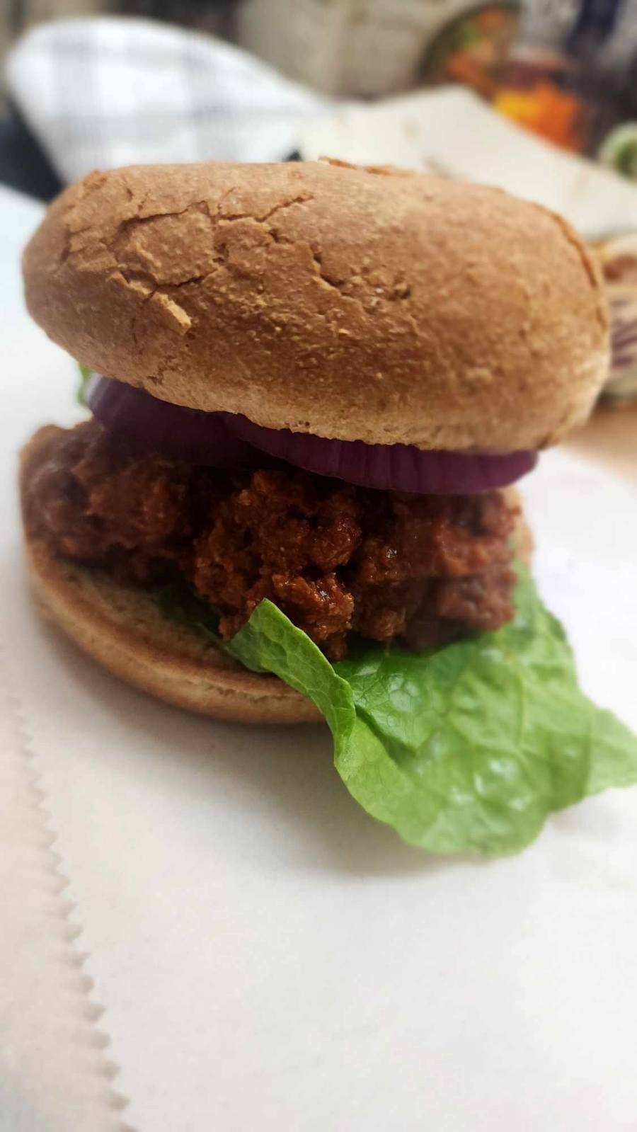 A close up of a hamburger with lettuce and onions on a plate.