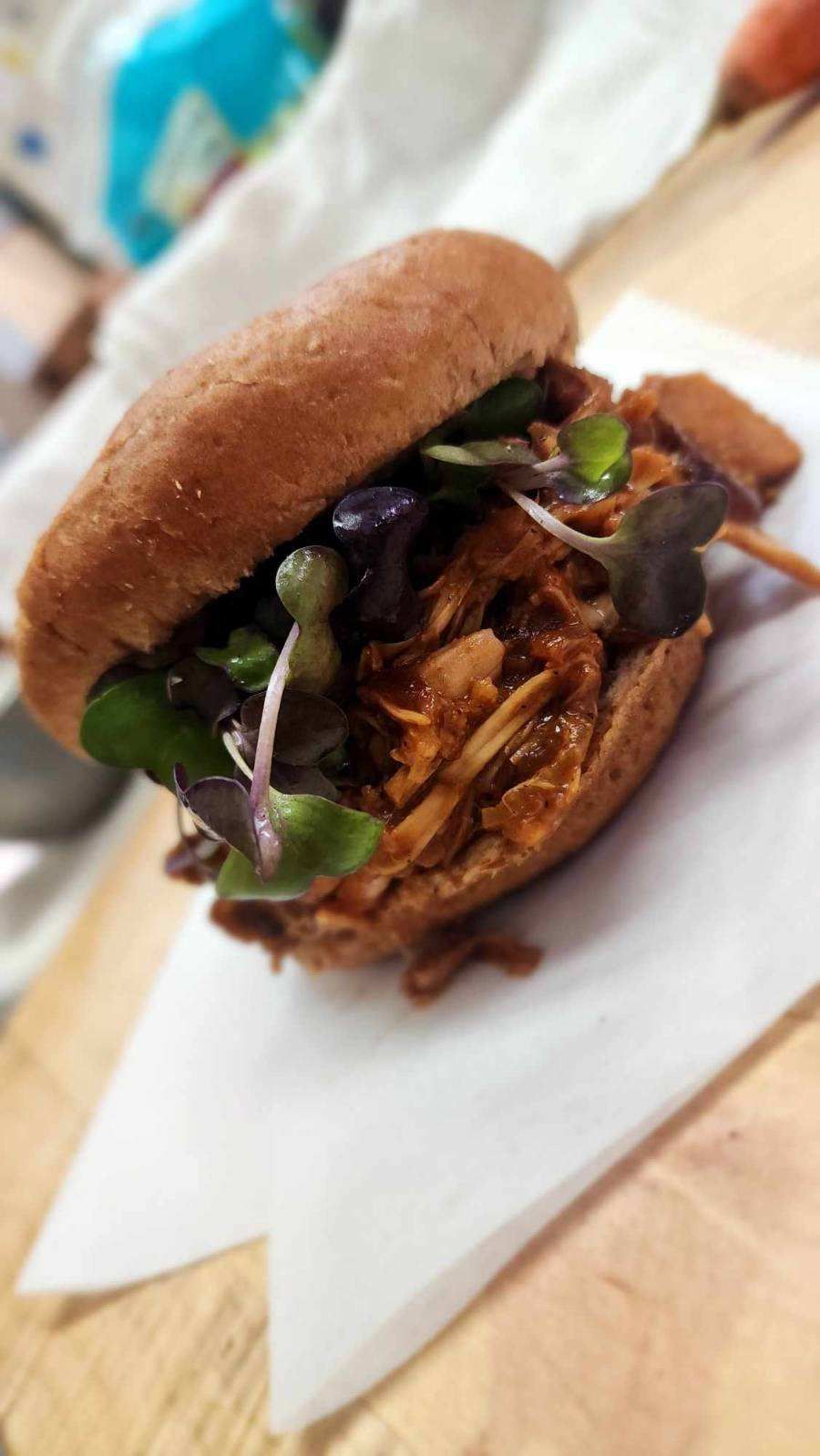A pulled pork sandwich is sitting on a piece of paper on a table.