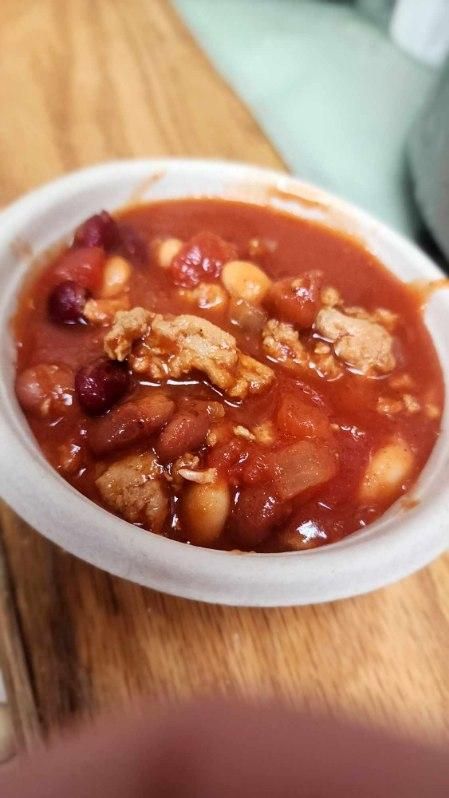 A bowl of chili is sitting on a wooden table.