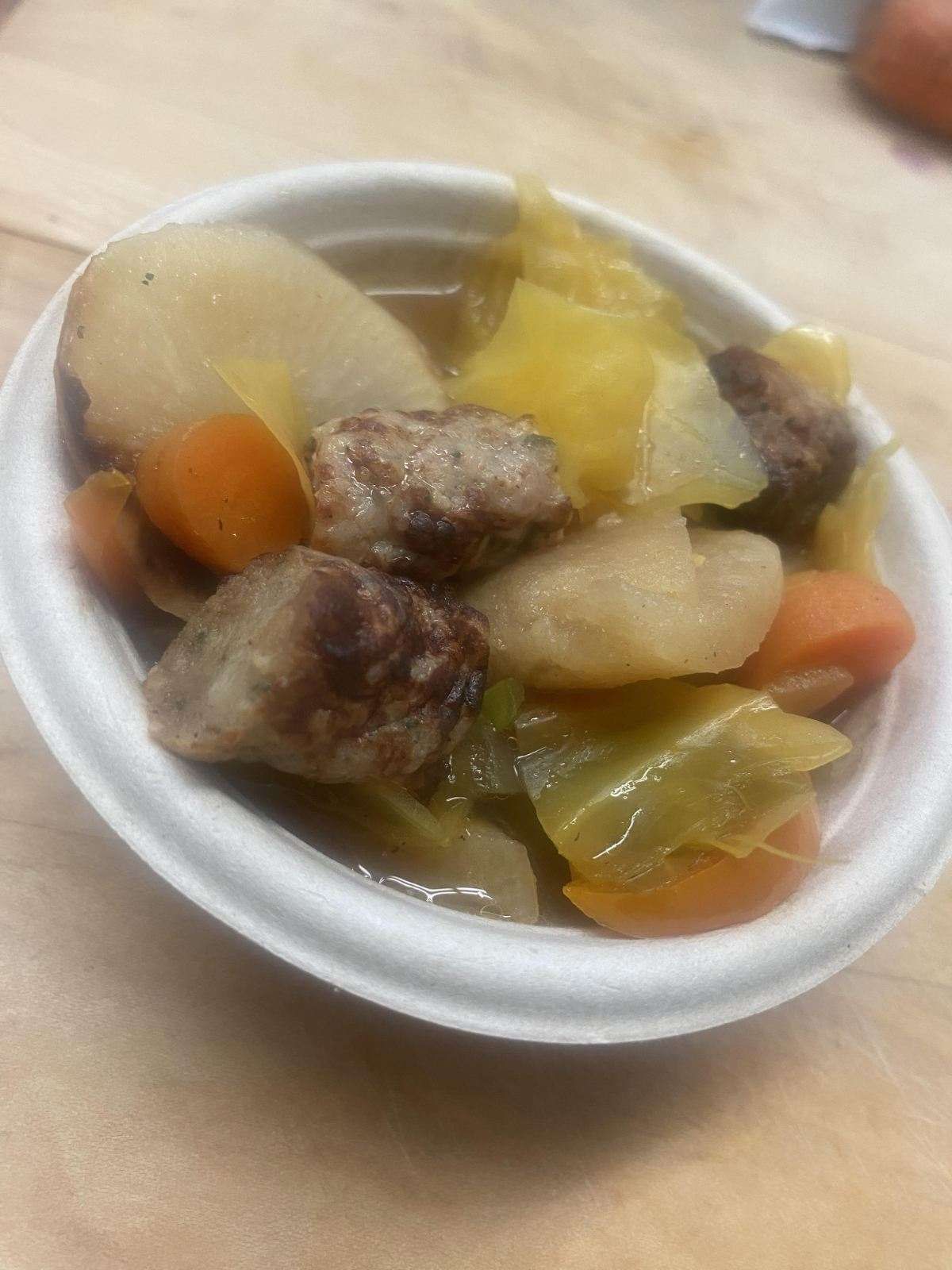 A bowl of food with meat and vegetables on a table.