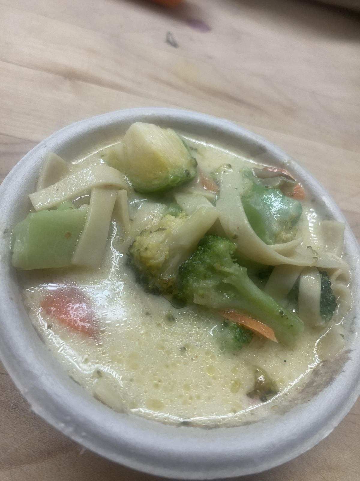 A close up of a bowl of soup with vegetables on a table.