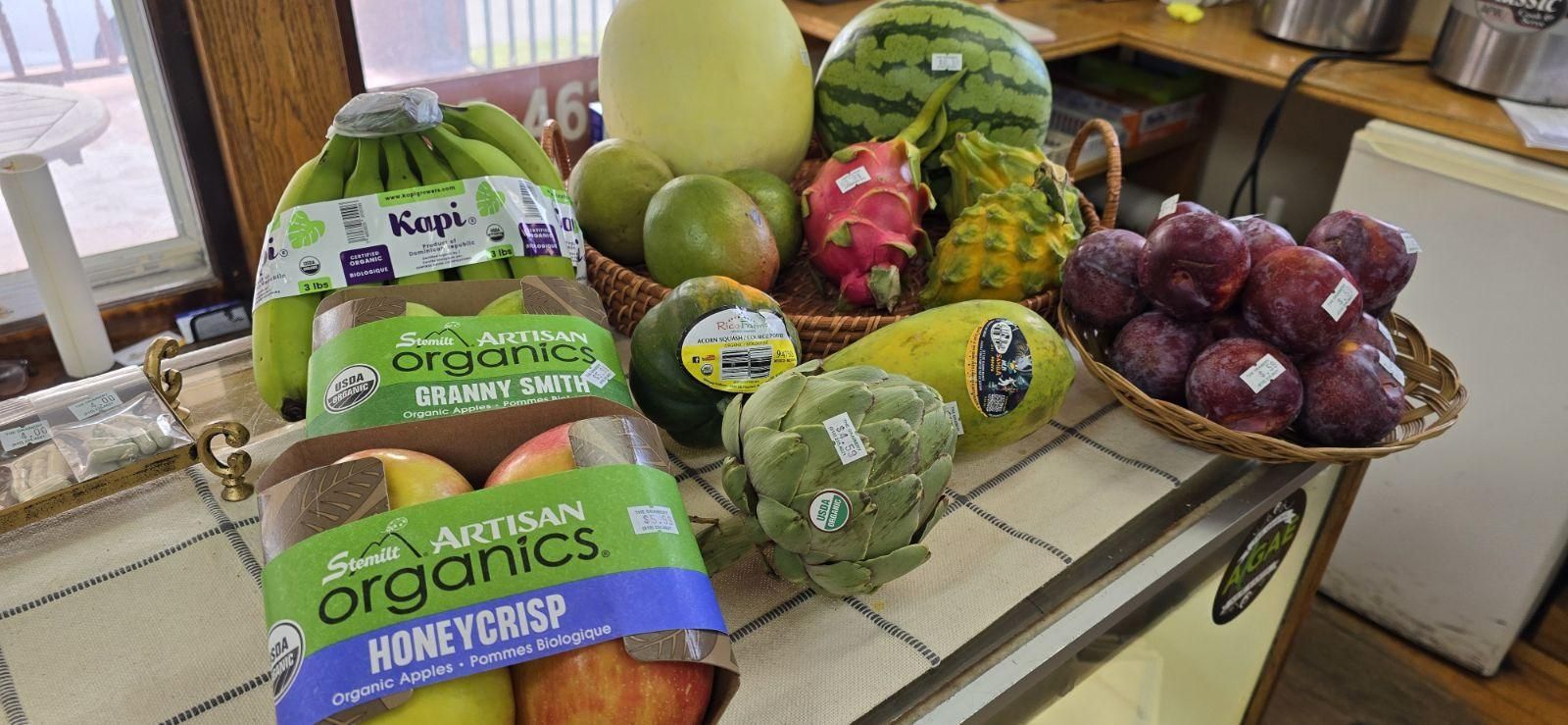 A variety of fruits and vegetables are sitting on a counter.