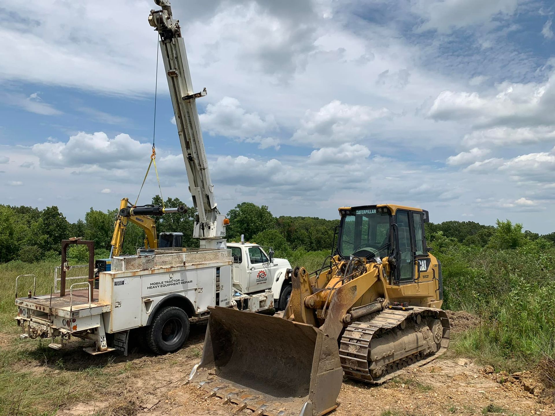 A bulldozer is parked next to a service truck in a field.