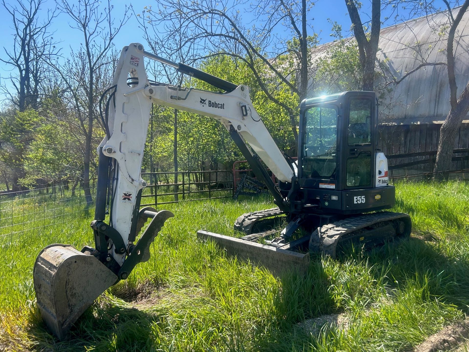 A small excavator is sitting in a grassy field.